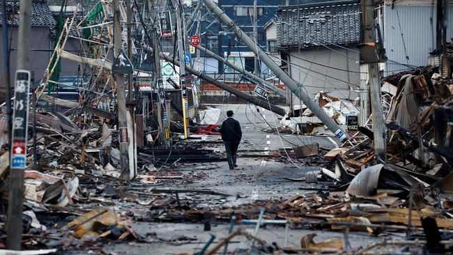 seorang-pria-berjalan-di-sepanjang-jalan-asaichi-dori-yang-terbakar-akibat-gempa-bumi-di-wajima-jepang-4-januari-2024_169